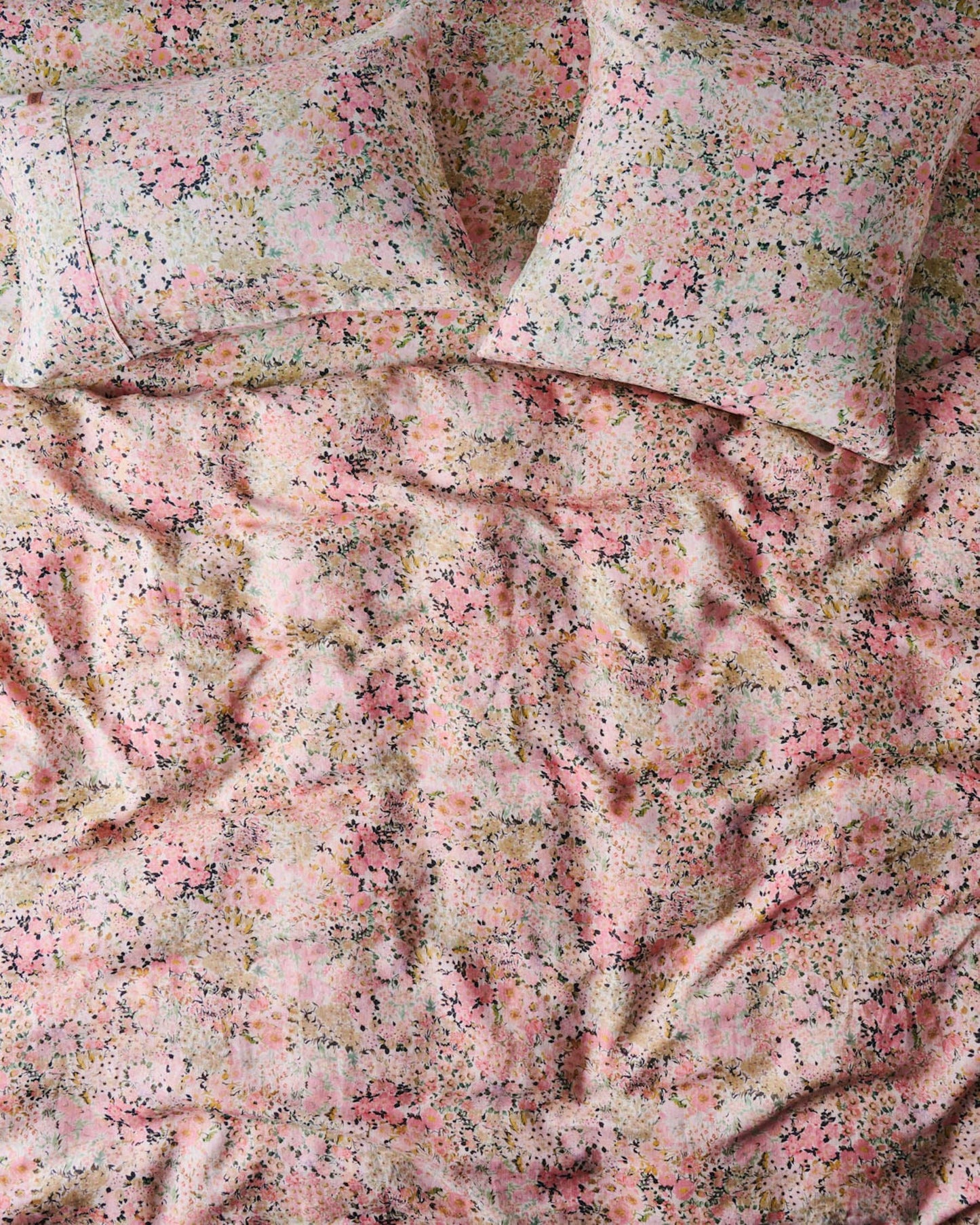 A fitted sheet with a floral pattern in shades of pink and green.
