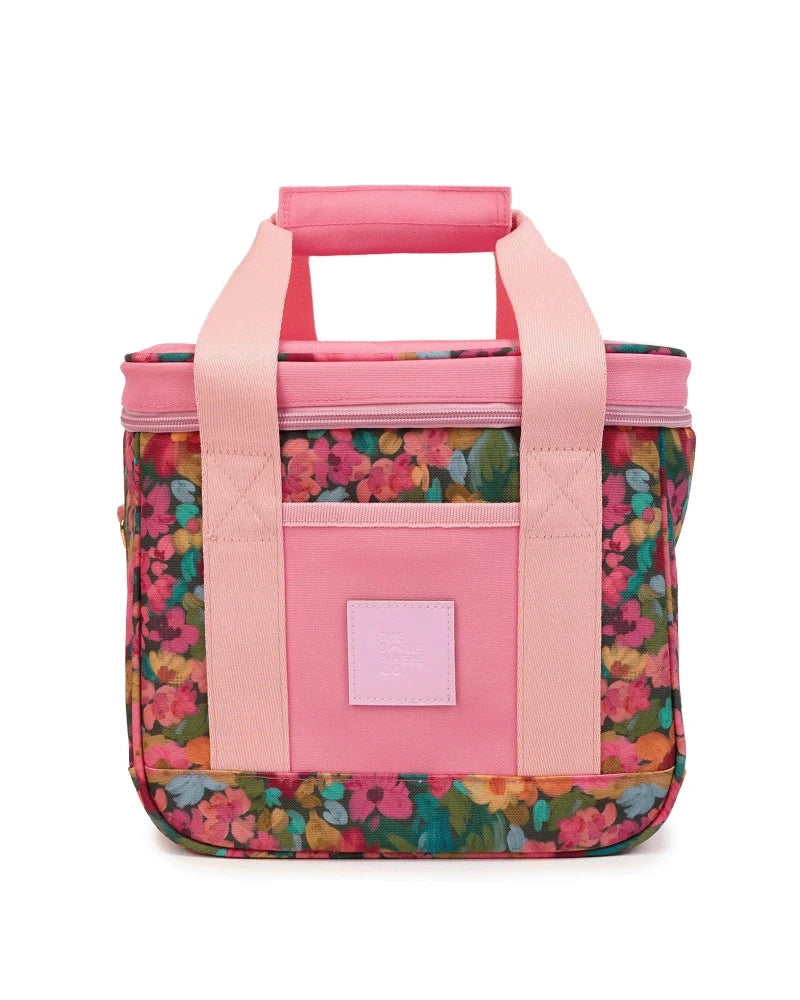 A pink handled lunch bag with a floral print body and solid pink straps, shown against a plain white background.