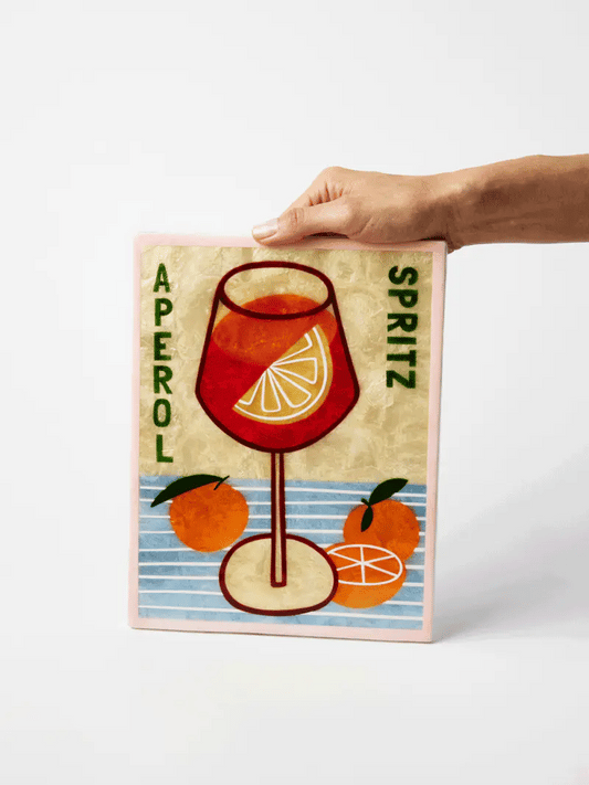 Framed artwork of Aperol Spritz with a hand holding it on a white background