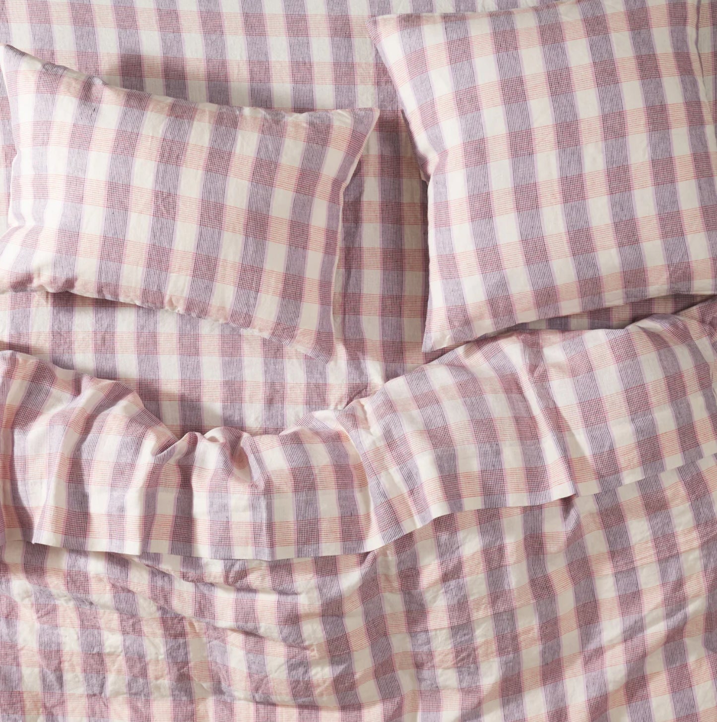 Checkered bedspread styled with matching quilt cover and pillowcases, blue, pink and cream checkered print.