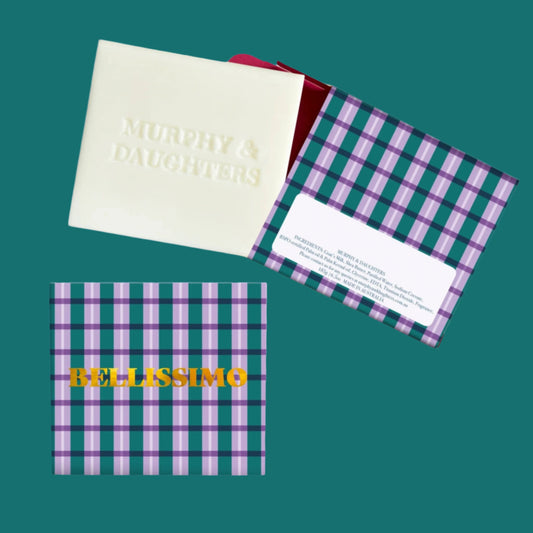 A bar of soap with 'BELLISSIMO' written on it, alongside a gold foiled box with a checkered pattern.