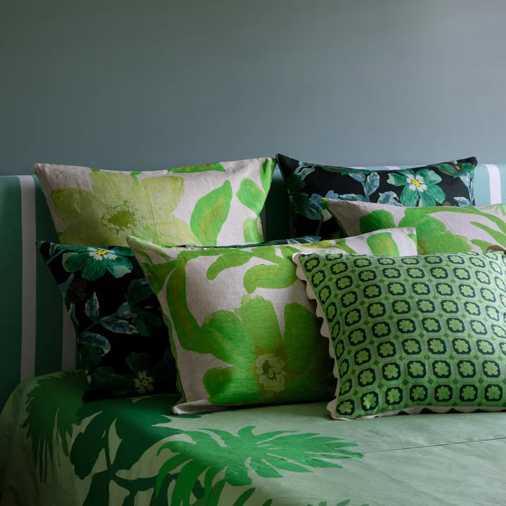 Green patterned floral cushions on a bed against a blue wall.