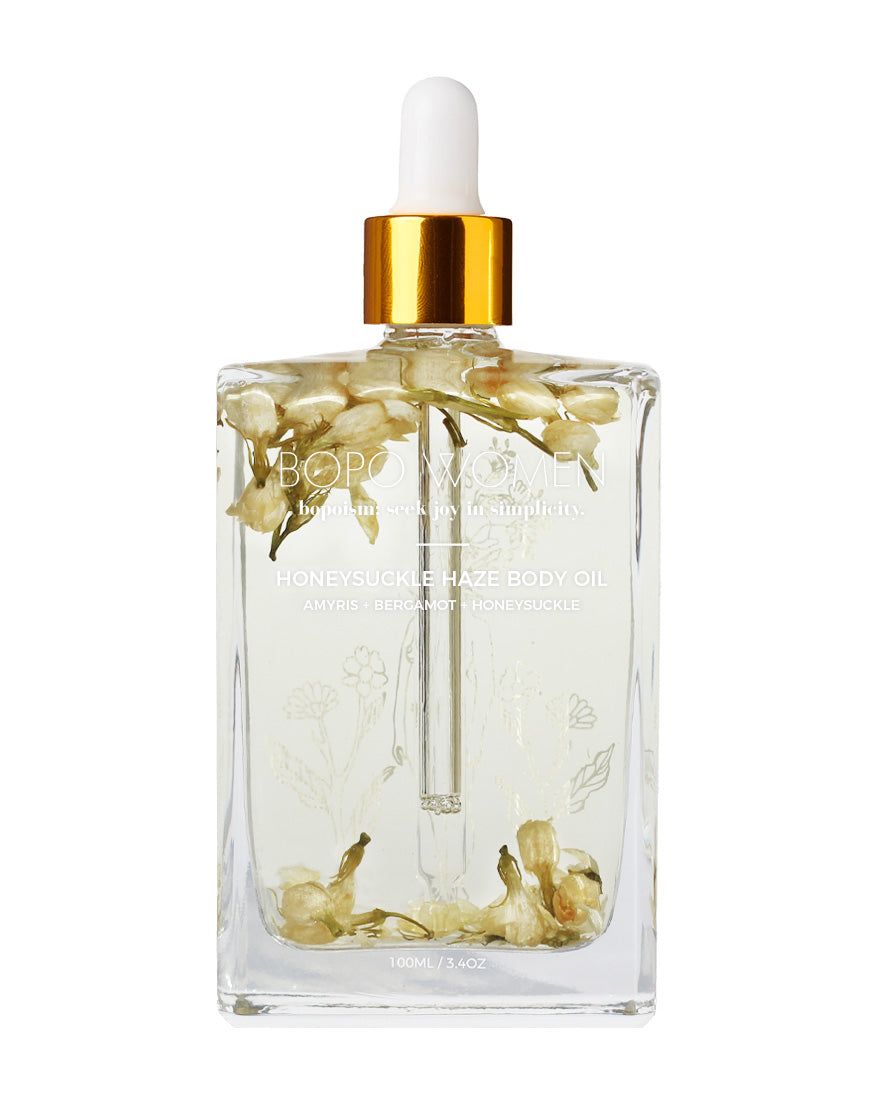Clear glass bottle with floral design and gold cap on a white background