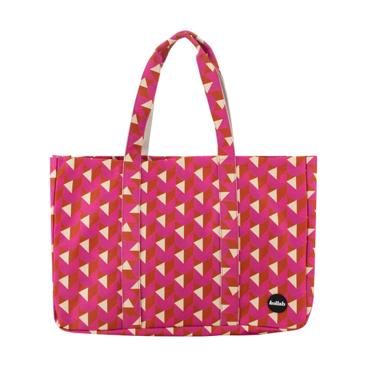 A tote bag with a geometric pattern of pink, orange, and cream triangles, featuring dual top handles and a small black circular 'allinlove' logo patch on the bottom right.