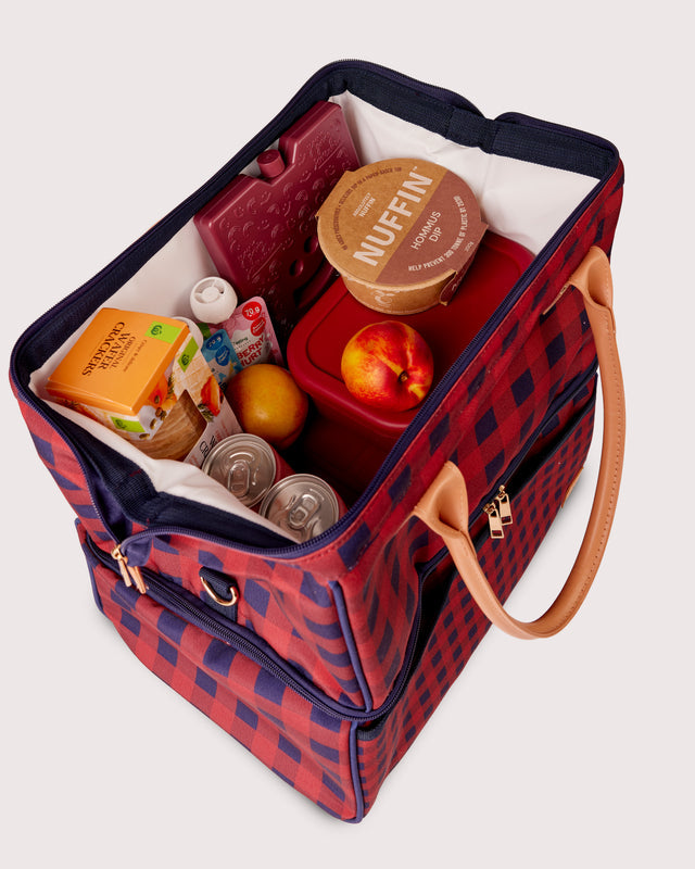 Red and blue checkered picnic basket with food items on a white background