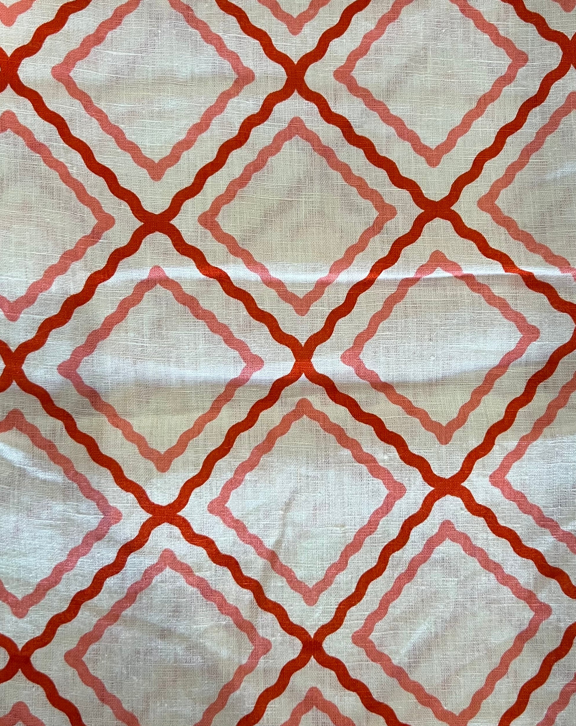 Fabric with red and pink geometric pattern on a beige background