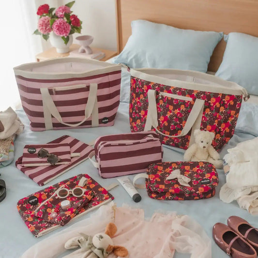 Assorted bag sizes sit on bed with blue bedding.
