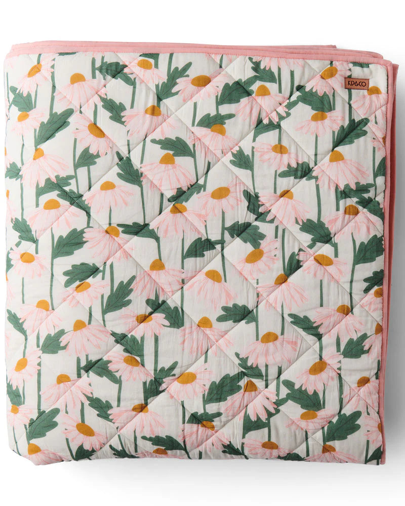 Floral patterned quilt with pink border on a white background