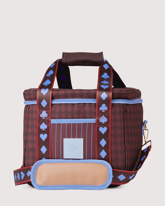 A structured tote bag with a dark red and purple diamond pattern, light blue piping, and blue-and-white striped handles decorated with spade and heart motifs. A beige front patch displays the 'The Happy Family' brand logo, and a matching patterned shoulder strap is draped in front.