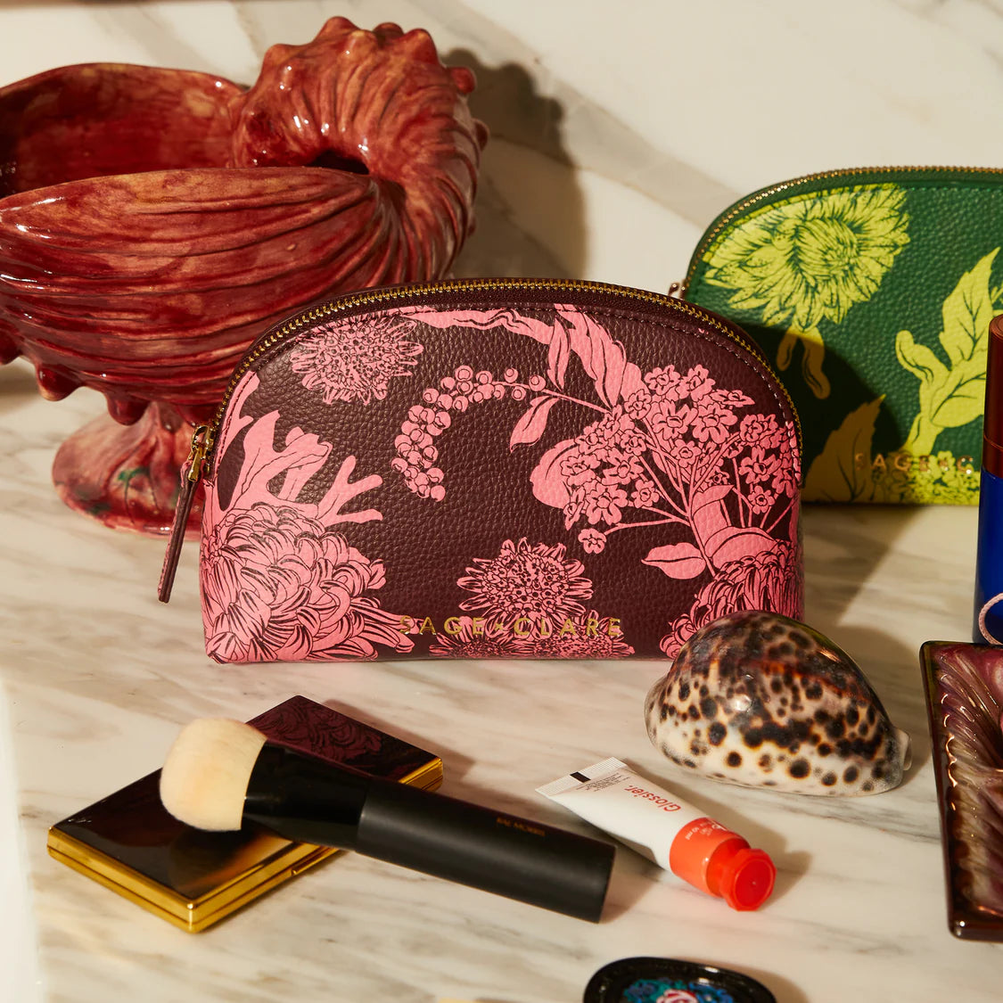Floral-patterned makeup bag on a table with makeup items and decorative objects.
