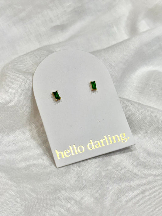 Green gemstone earrings on a 'hello darling' card against a white fabric background