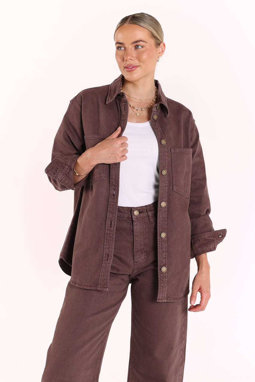 Woman wearing a brown jacket and pants on a white background