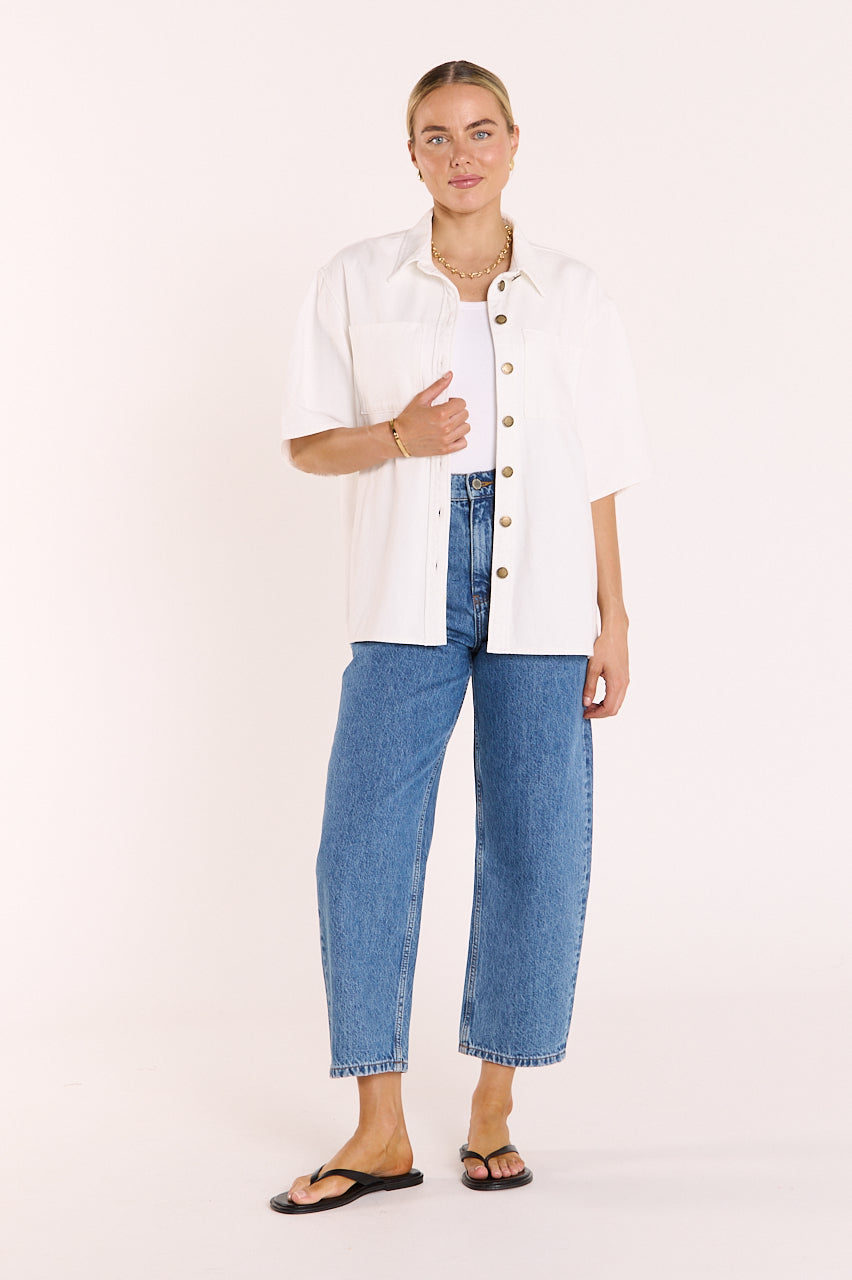 Woman wearing a white blouse and blue jeans on a plain background