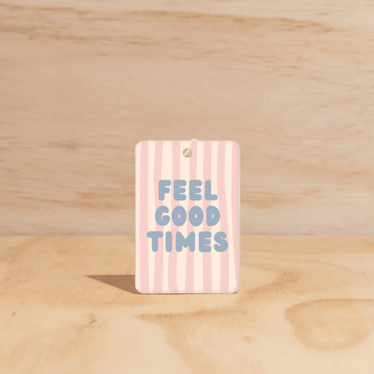 Striped car freshener with 'FEEL GOOD TIMES' text on a wooden surface