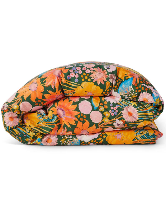 A quilt cover with a floral print in shades of pink, orange, and yellow on a deep green base, with a plain melon pink reverse.