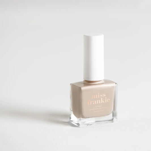 Nail polish bottle with 'miss frankie' branding on a light gray background. Pale nude/grey colour polish. 
