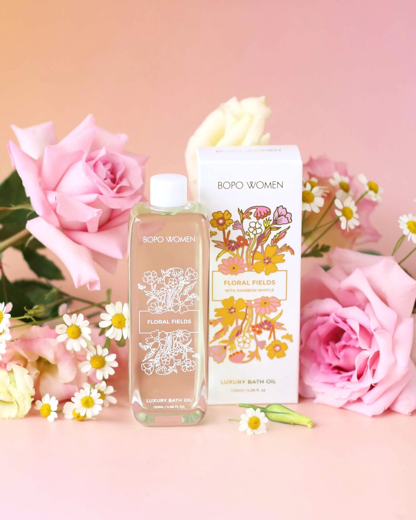 Bottle of bath oil and packaging on a pink floral background