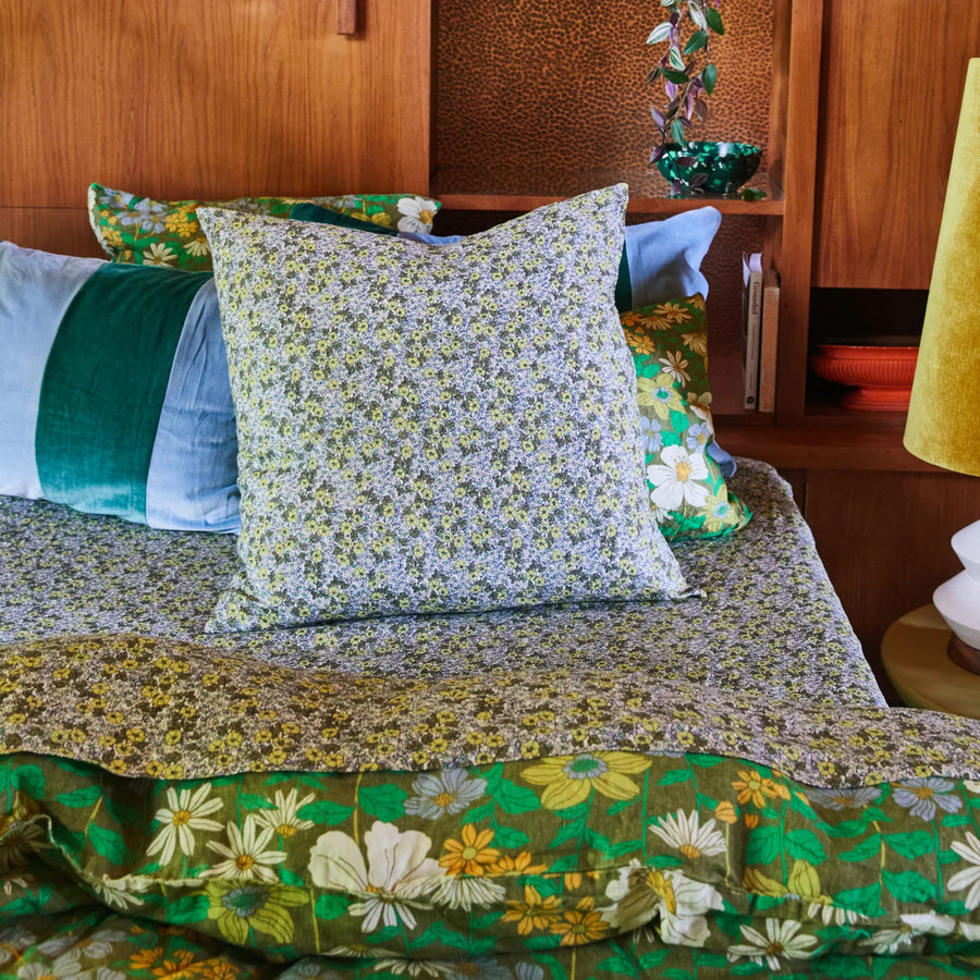 Floral bedding and pillows on a bed with a wooden headboard.