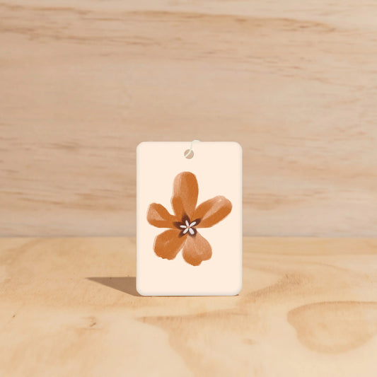 Rectangular white tag with a brown flower design on a wooden surface