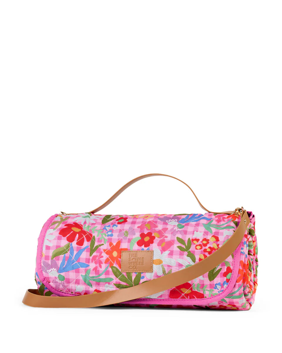 Floral patterned picnic rug with a brown strap on a white background