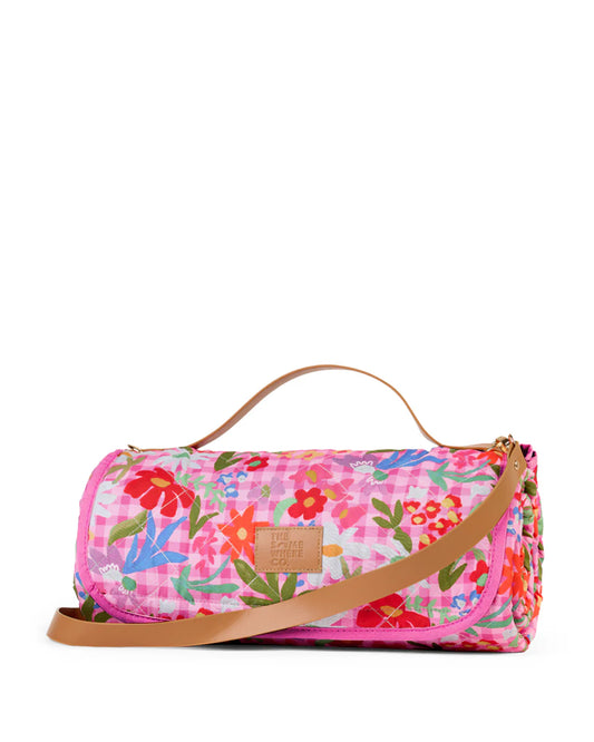 Floral patterned picnic rug with a brown strap on a white background