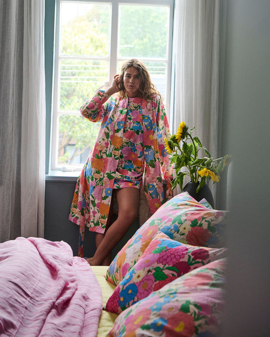 Woman stands in window frame wearing matching robe and nightie.