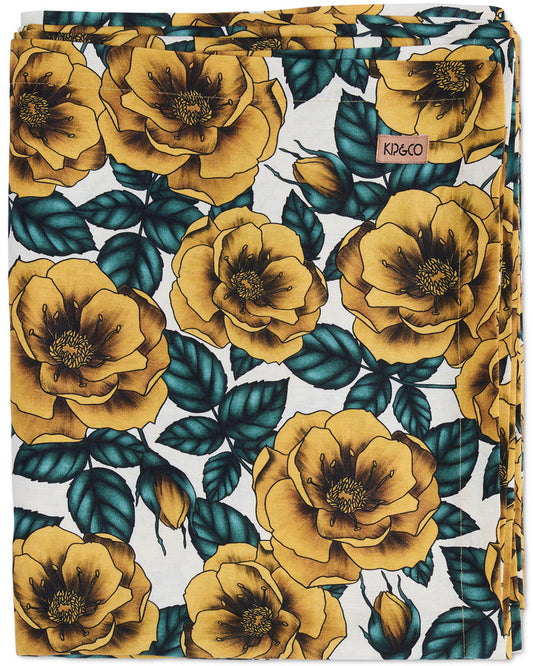 Floral patterned fabric with yellow flowers and green leaves on a white background, featuring the brand 'Koko'.