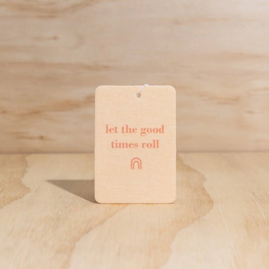 Car freshener with 'let the good times roll' text on a wooden surface