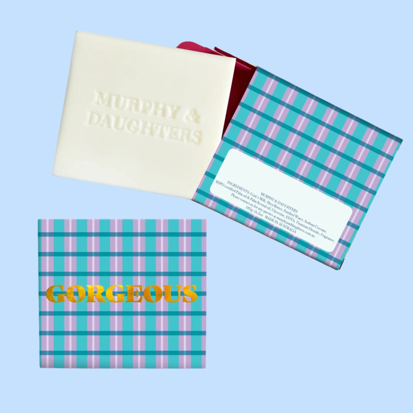 A bar of soap with 'GORGEOUS' written in yellow on a purple checkered background, and a gold foiled box with the name 'GORGEOUS' on it.