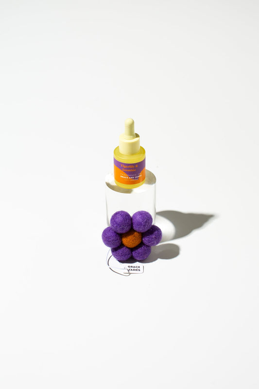 Bottle with a yellow cap dropper and purple flower air freshener on a white background
