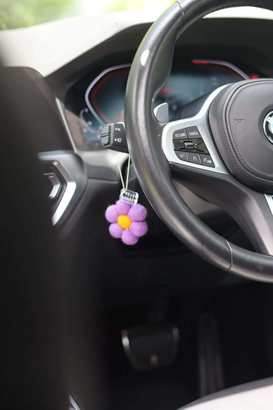 Purple flower-shaped car air freshener hanging from a car dashboard.
