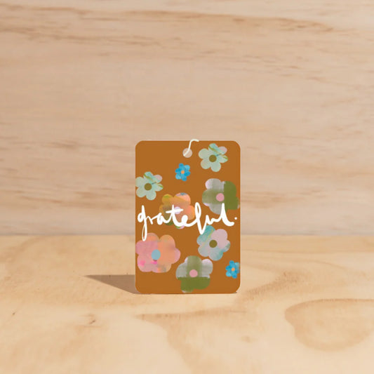 Card with floral designs and the word 'grateful' on a wooden surface