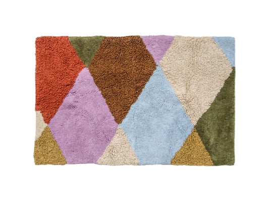 A colorful geometric patterned Harlequin Bath Mat laid out on a plain background.