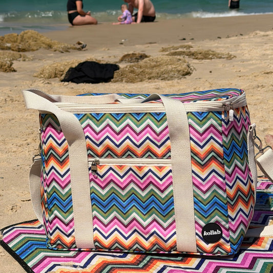 Picnic bag with assorted colours in zag zag pattern sit on beach with picnic bag in matching print.