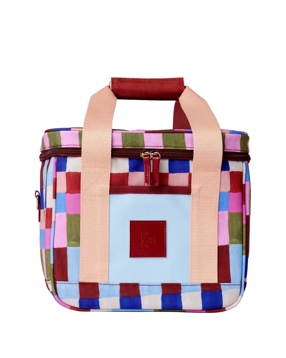 A square canvas tote bag featuring a colorful patchwork pattern of pink, blue, green, and red squares, with light peach-pink handles and a dark red leather patch on the front.