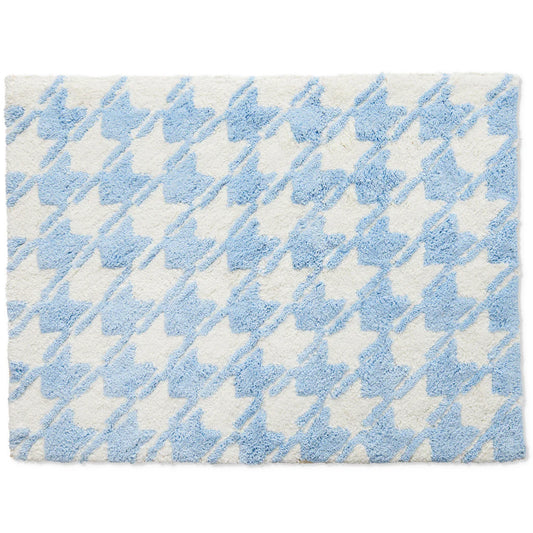 Blue and white houndstooth patterned bath mat on a plain background.