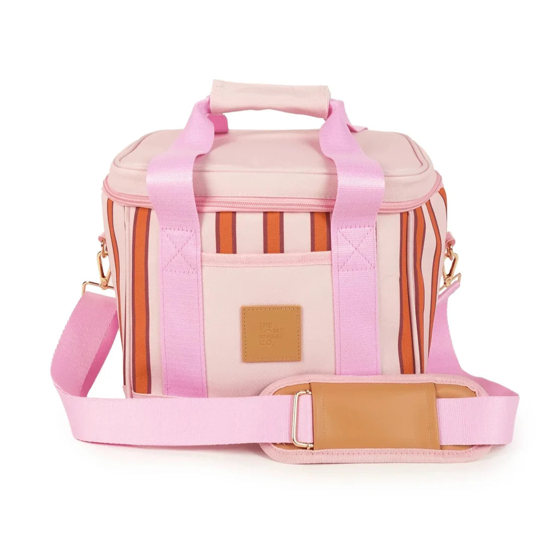 A pink insulated tote bag with a striped pattern in pink, orange, and white, featuring a top handle, a detachable pink shoulder strap, and a tan leather patch on the front pocket.