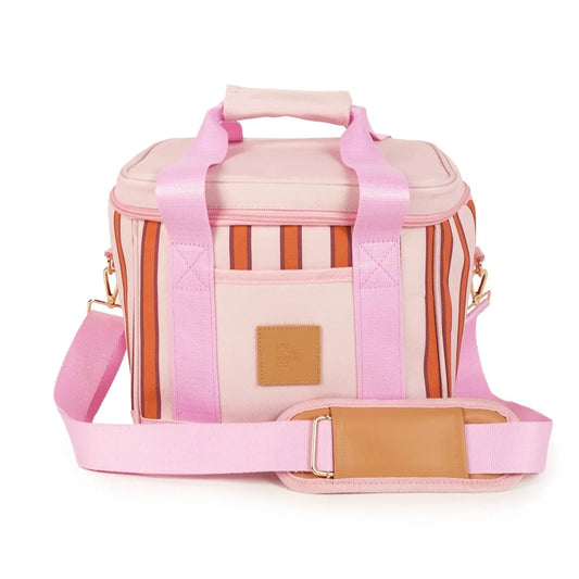 A pink insulated tote bag with a striped pattern in pink, orange, and white, featuring a top handle, a detachable pink shoulder strap, and a tan leather patch on the front pocket.