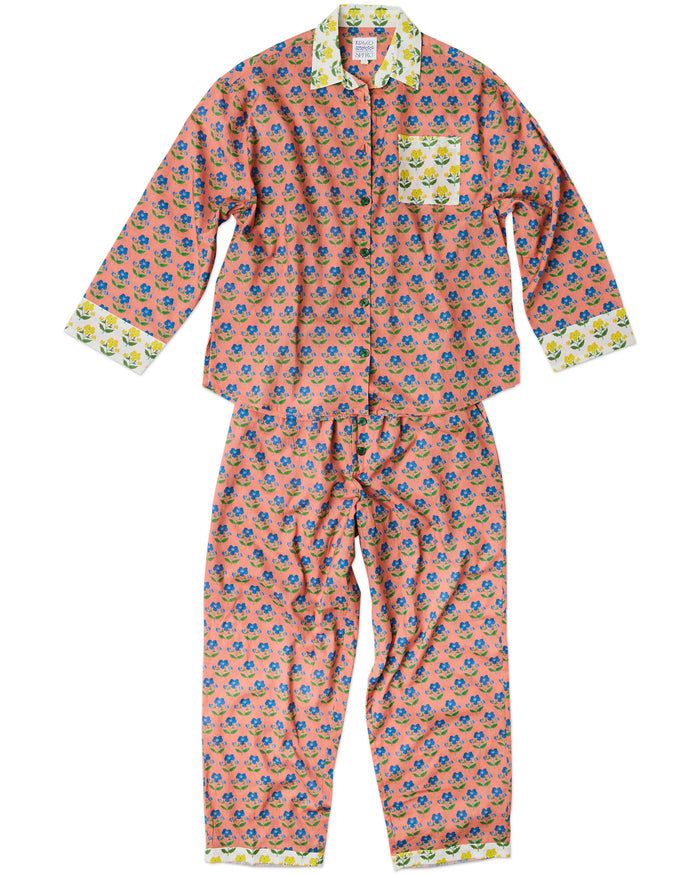 A two-piece long-sleeve pajama set featuring a pink base with a colorful floral pattern, a contrasting light green, yelllow and white patterned collar, cuffs, and chest pocket, and a matching drawstring waistband.