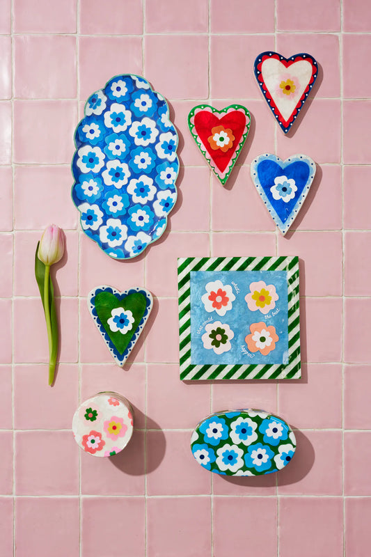 Decorative ceramic tiles with floral and heart designs on a pink tiled background