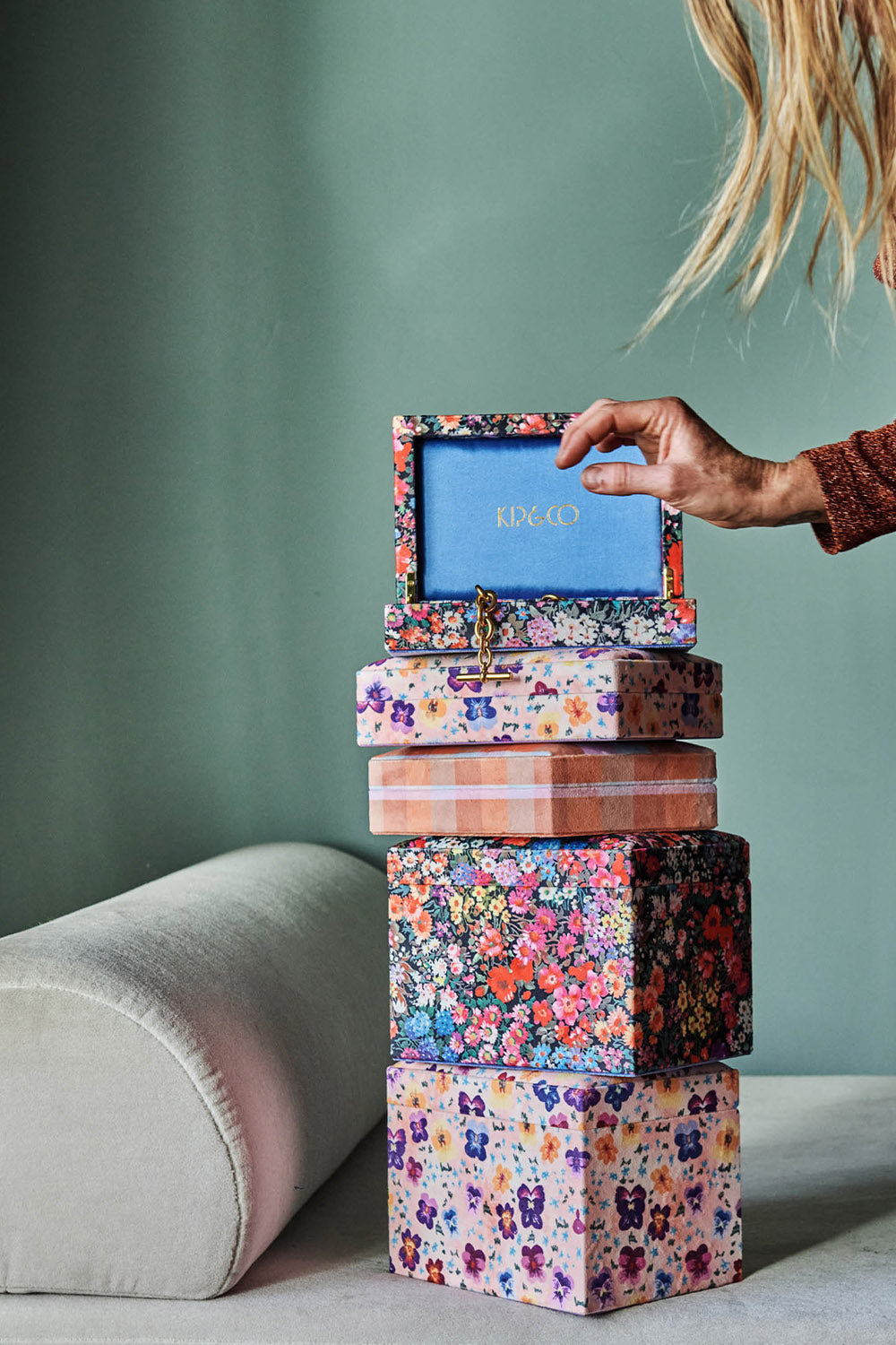 Five velvet jewellery boxes in various sizes stacked on top of one another. Two sizes, various floral and plaid prints. 
