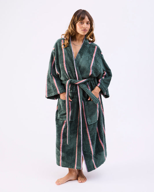 Woman wearing a green robe with pink stripes on a white background