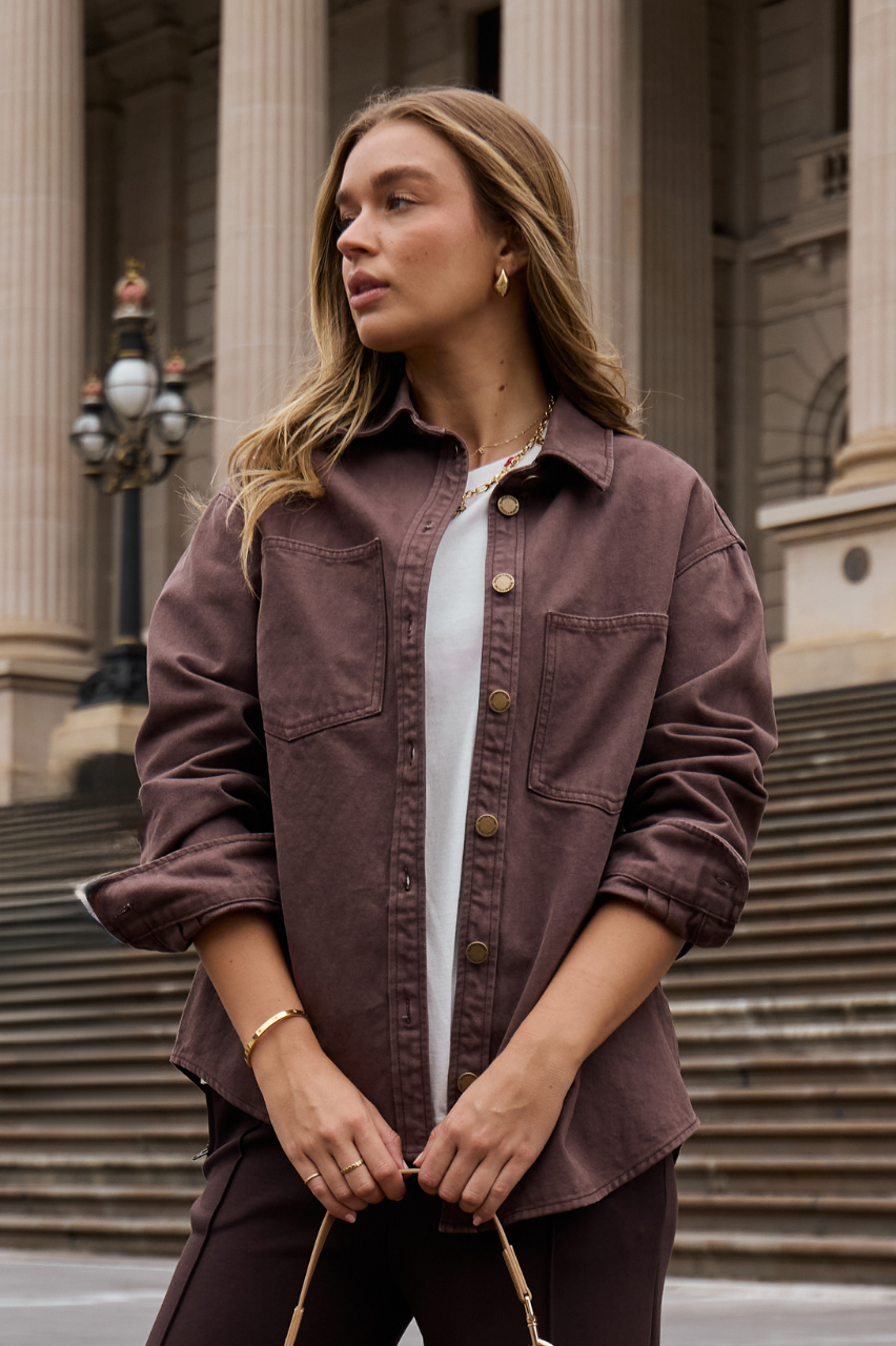 Woman wearing a brown jacket in front of a building