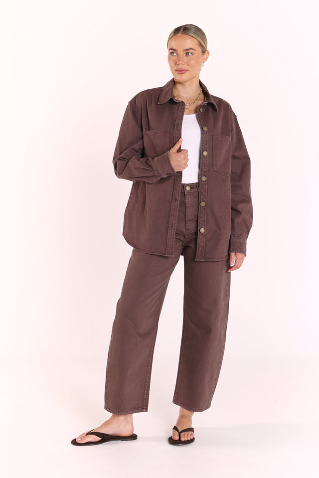 Woman wearing a brown button-up shirt and pants on a white background