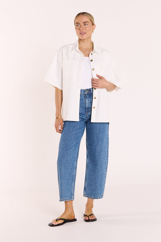 Woman wearing a white shirt and blue jeans on a plain background
