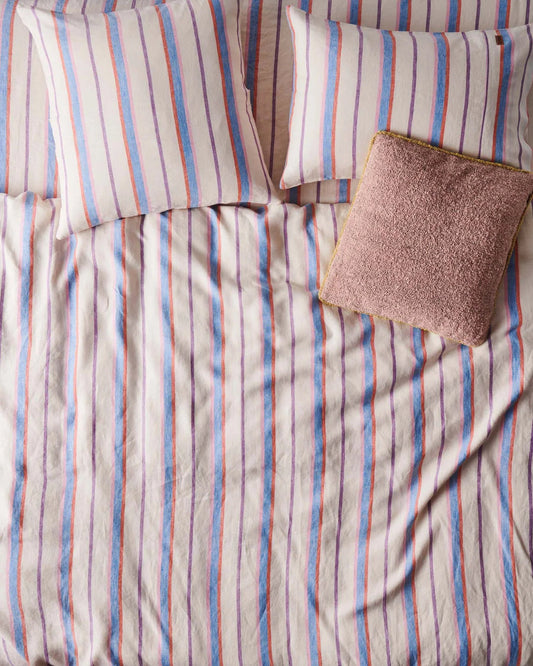 Striped bedspread with a pillow and textured square pillow  on a bed