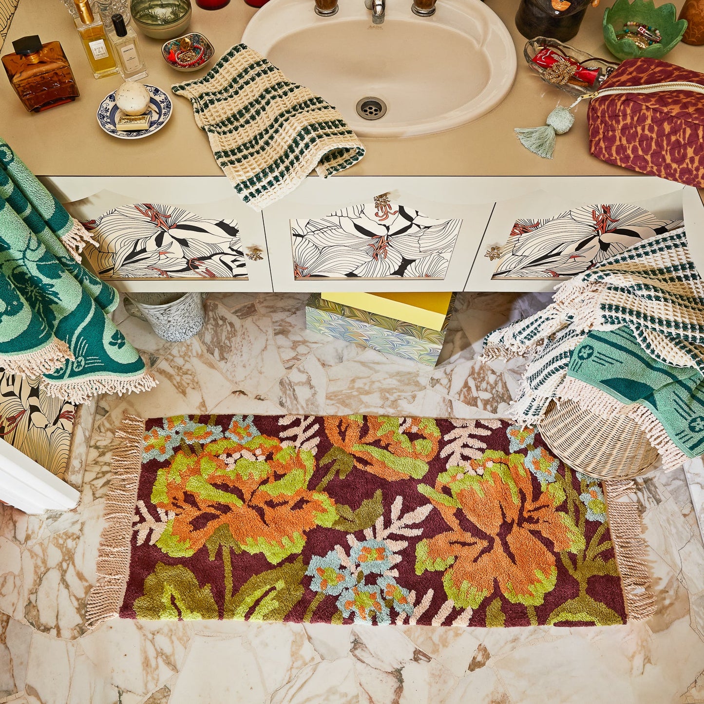 Bathroom counter with decorative towels and a floral bath runner.