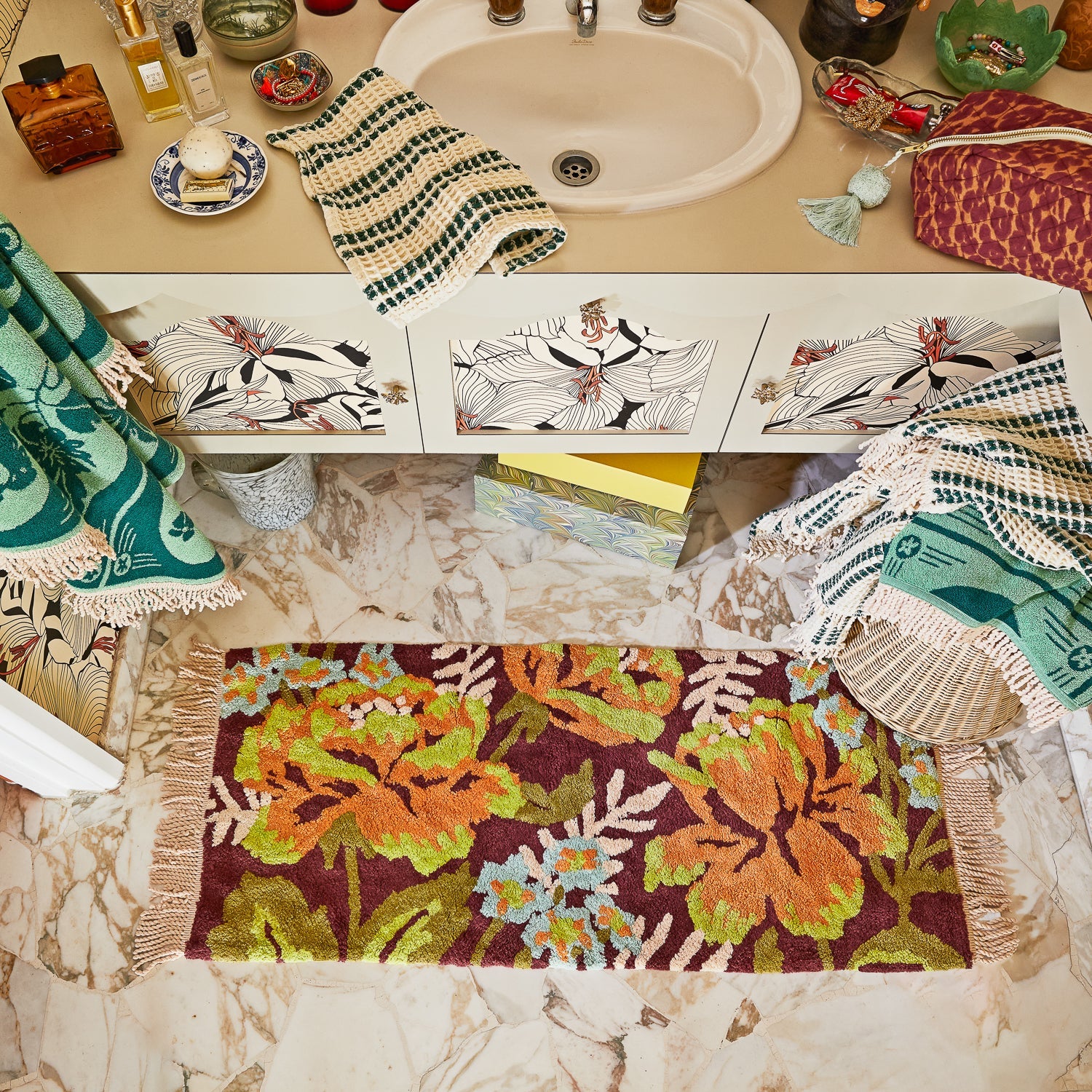 Bathroom counter with decorative towels and a floral bath runner.