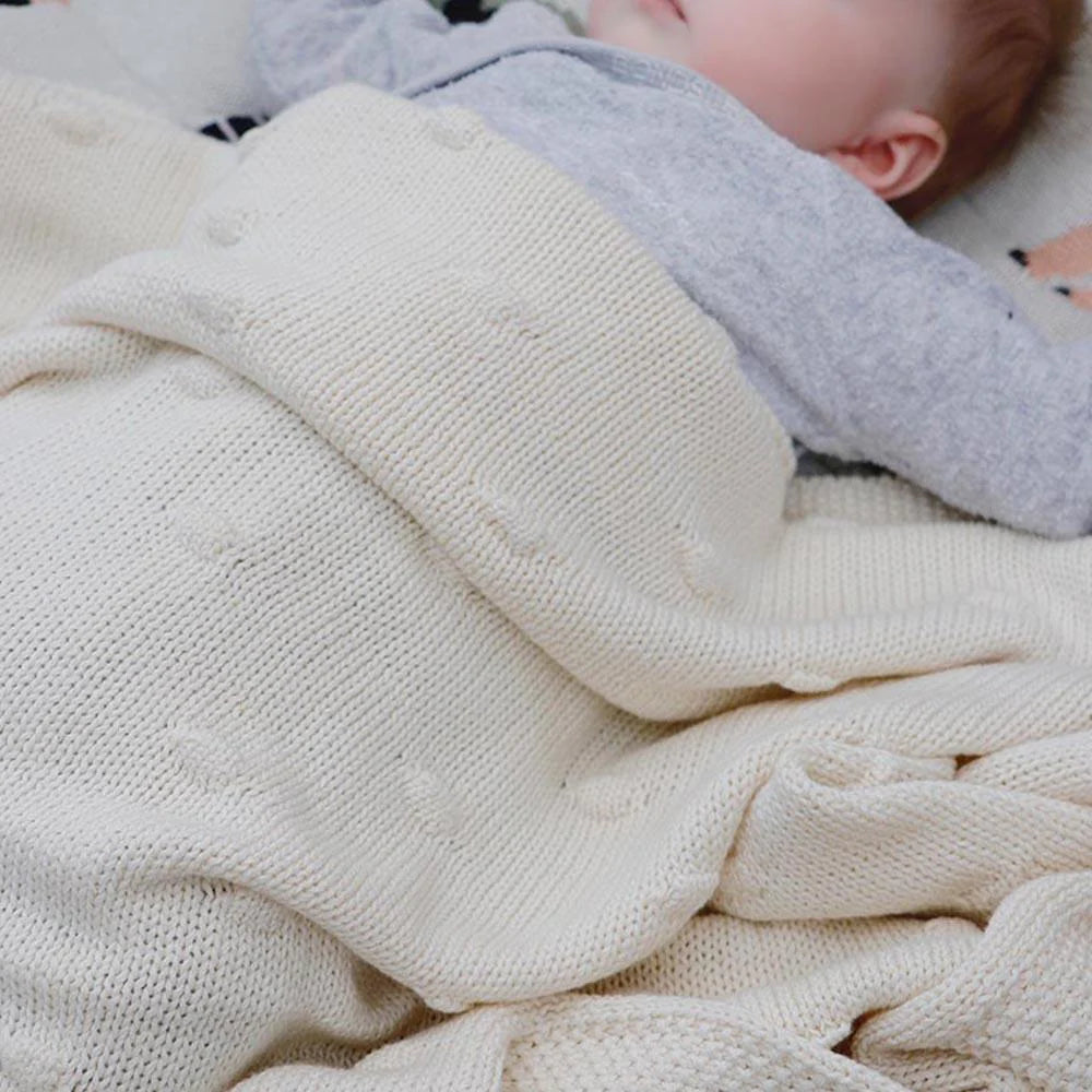 Baby wrapped in a white blanket with a blurred background