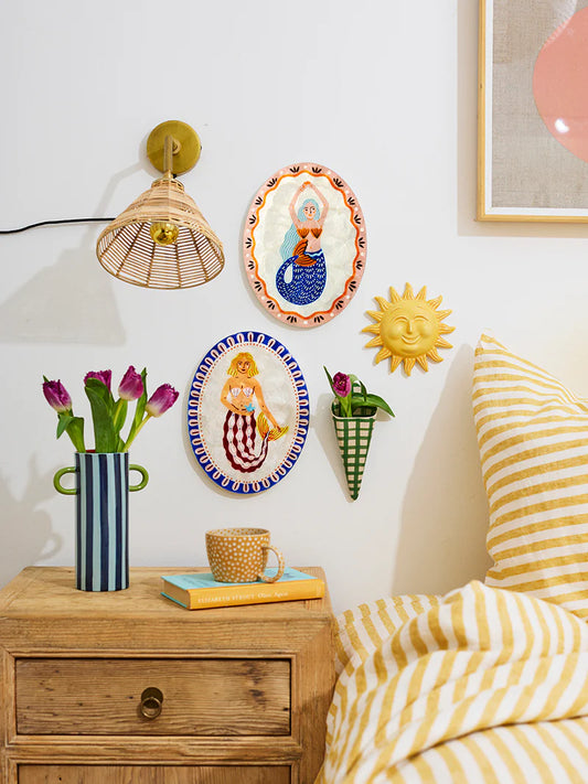 Decorative wall art and bedside table with a striped pillow in a room setting.